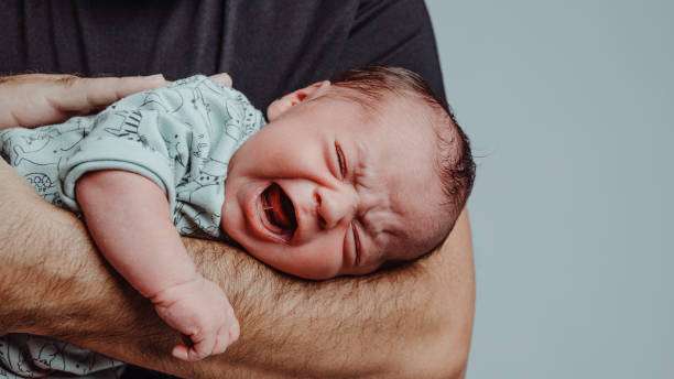 The baby is crying while wearing a Baby Sleep Sack.