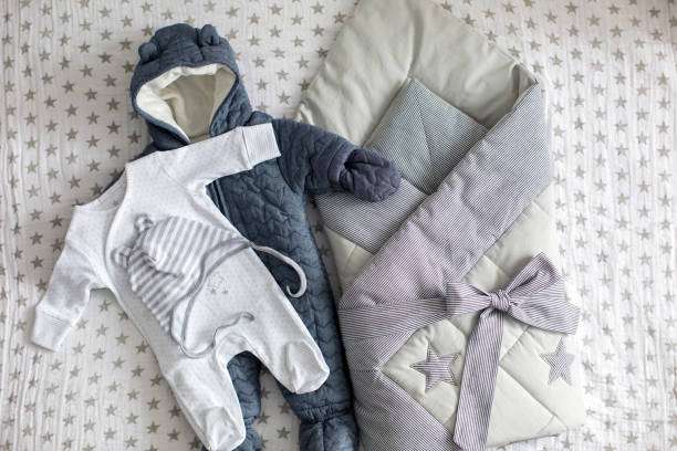 Newborn baby sleep sack, blue romper, and white onesie with star theme.